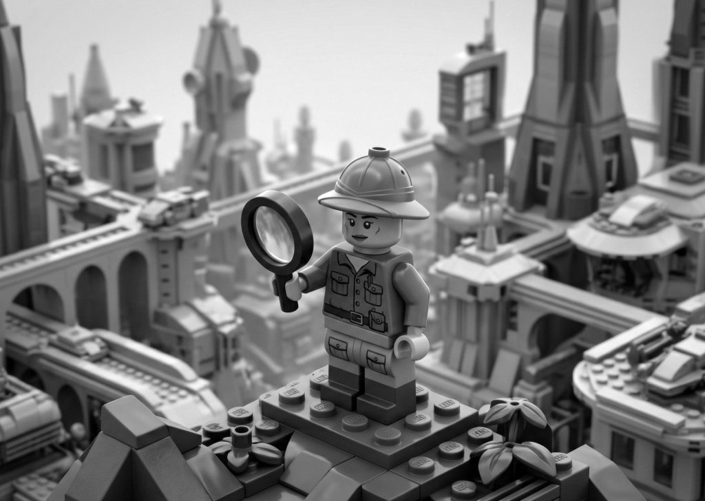 Black and white Lego explorer holding a magnifying glass overlooking a detailed Lego city skyline, symbolizing market research and strategic mobile app marketing.