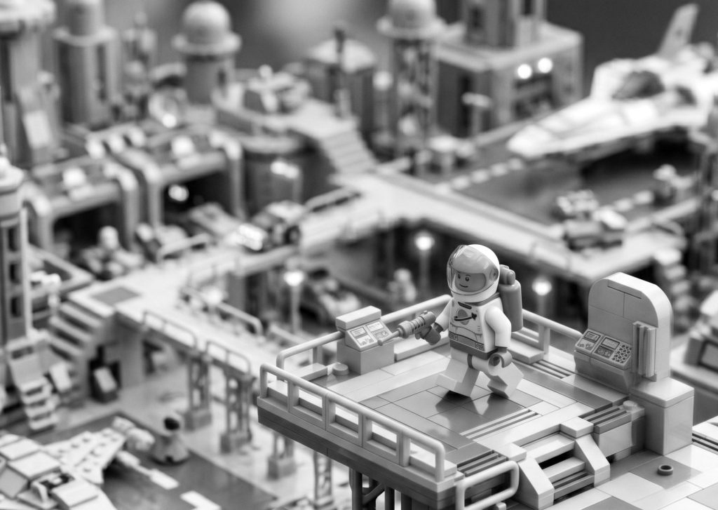 Black and white Lego astronaut standing on a futuristic space station platform, symbolizing a successful launch and deployment with professional app publishing services.
